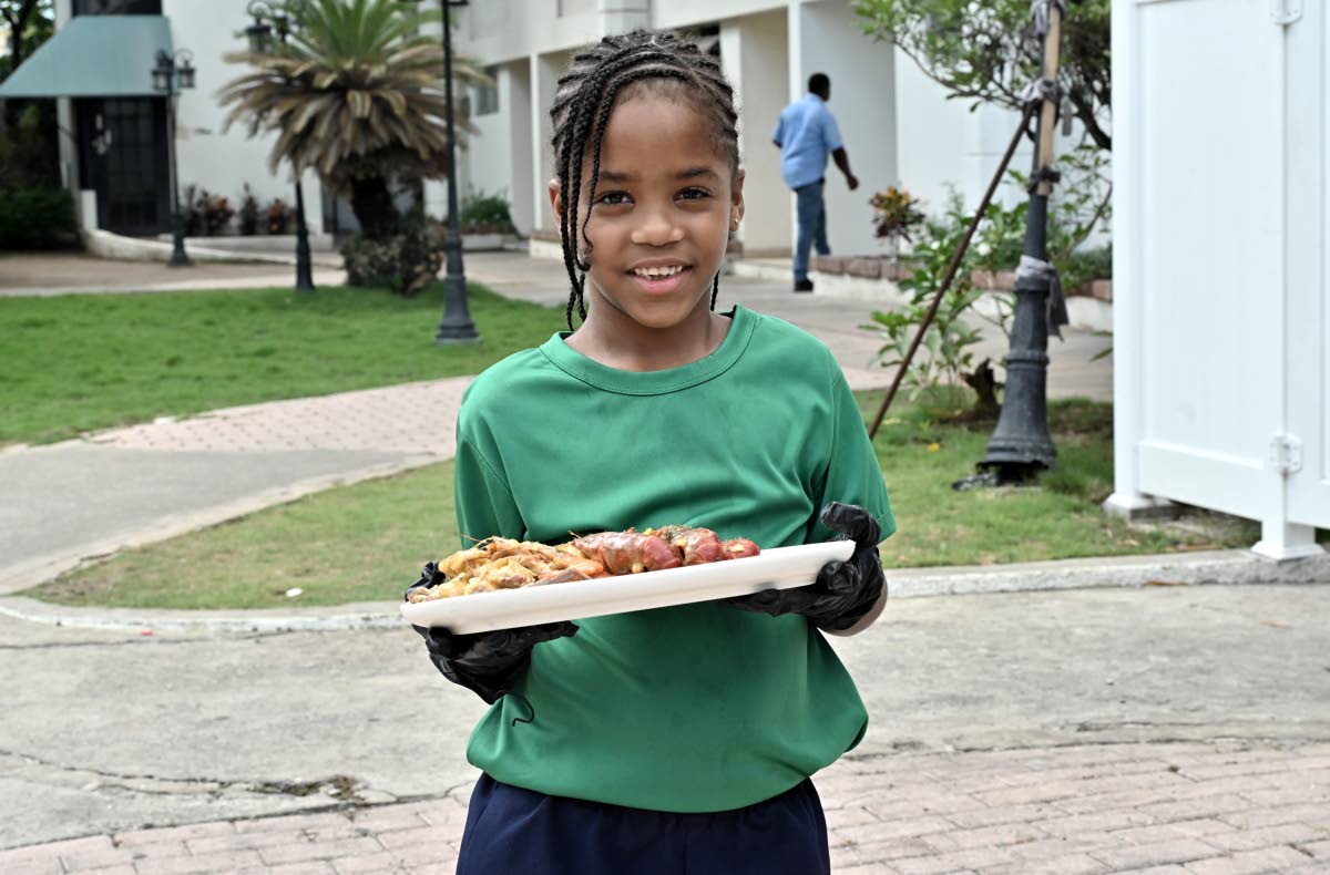 Chef Jonathan Simpson’s daughter, Jay-Ann Simpson, smiles for the camera as she presents one of her father’s signature dishes: the seafood boil.