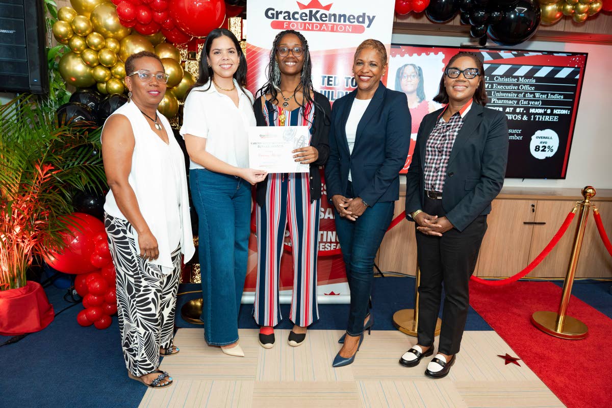 Corone Morris (centre), first-year pharmacy student at The University of the West Indies, Mona, is presented with a tertiary bursary award by Zoe Alexander (second left), granddaughter of the late Carlton Alexander, during the Carlton Alexander Memorial Bu