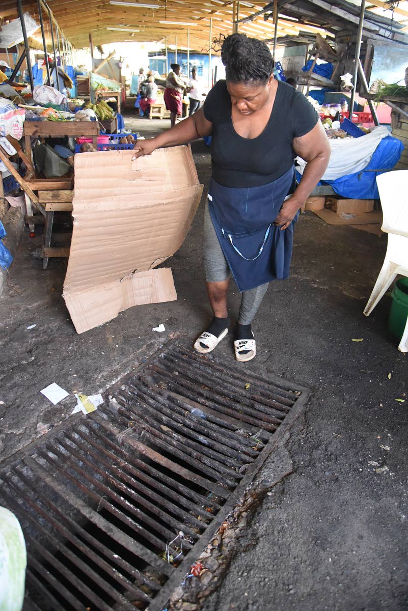 Market vendor Dorey McPherson shows the yet-to-be-repaired drain in which she injured her leg inside the Morant Bay Market last December.