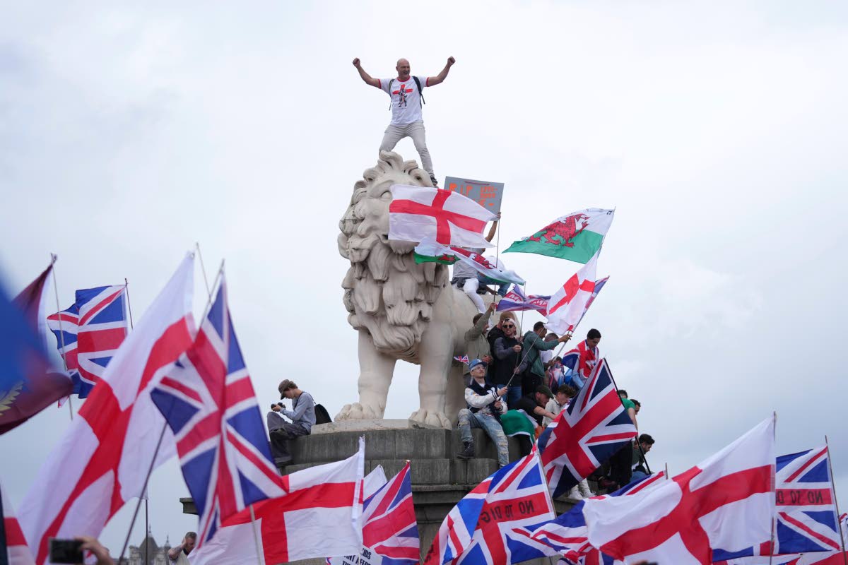 A demonstrator stands on the head of the South Bank lion that sits on the side of the Westminster Bridge, during a Tommy Robinson-led Unite the Kingdom march and rally in London on Saturday.