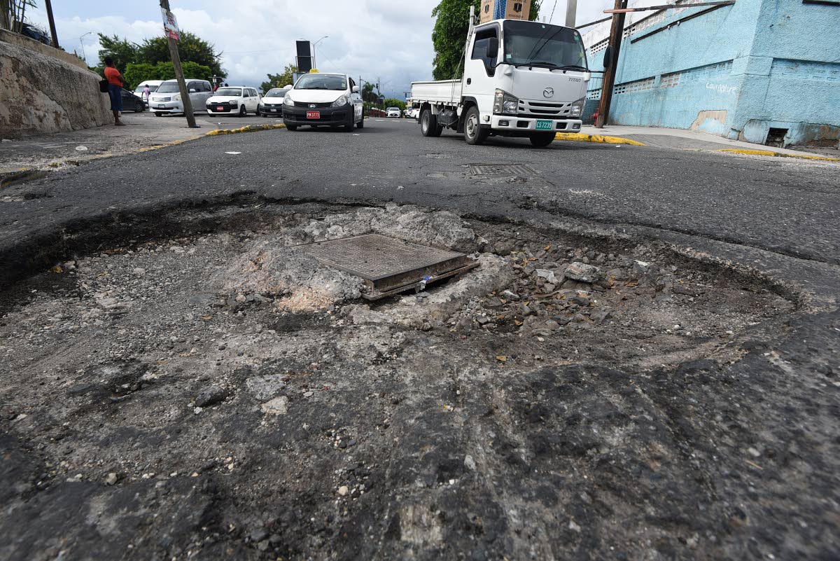 A pothole stretches across Church Street at the junction of Law Street in downtown Kingston, forcing motorists to drive along a narrow ledge along the sidewalk to avoid it. The pothole has been present for several months, getting wider as a result of recen