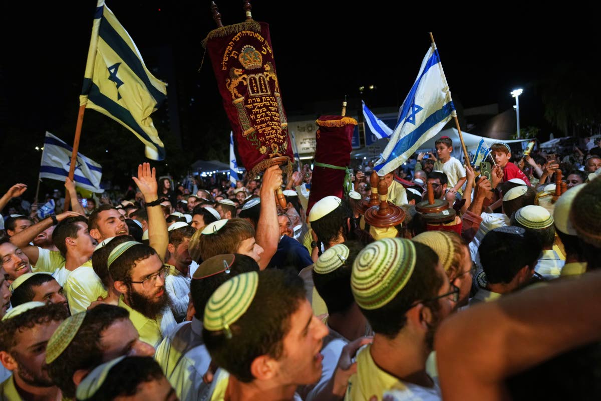 Jewish revellers dance and hold up the Torah as they celebrate the holiday of Simchat Torah at the plaza known as ‘Hostages Square’ in Tel Aviv, Israel, on Tuesday, October 14.
