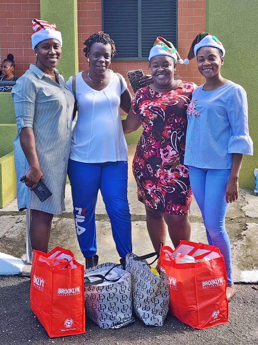 An unnamed parent, (second left) poses with guidance counsellors, from left, Tena Williams-Leslie, Imani Gordon, and Yolisa Passley after collecting her grocery basket, during the Holiday Helpers’ annual treat in 2023.