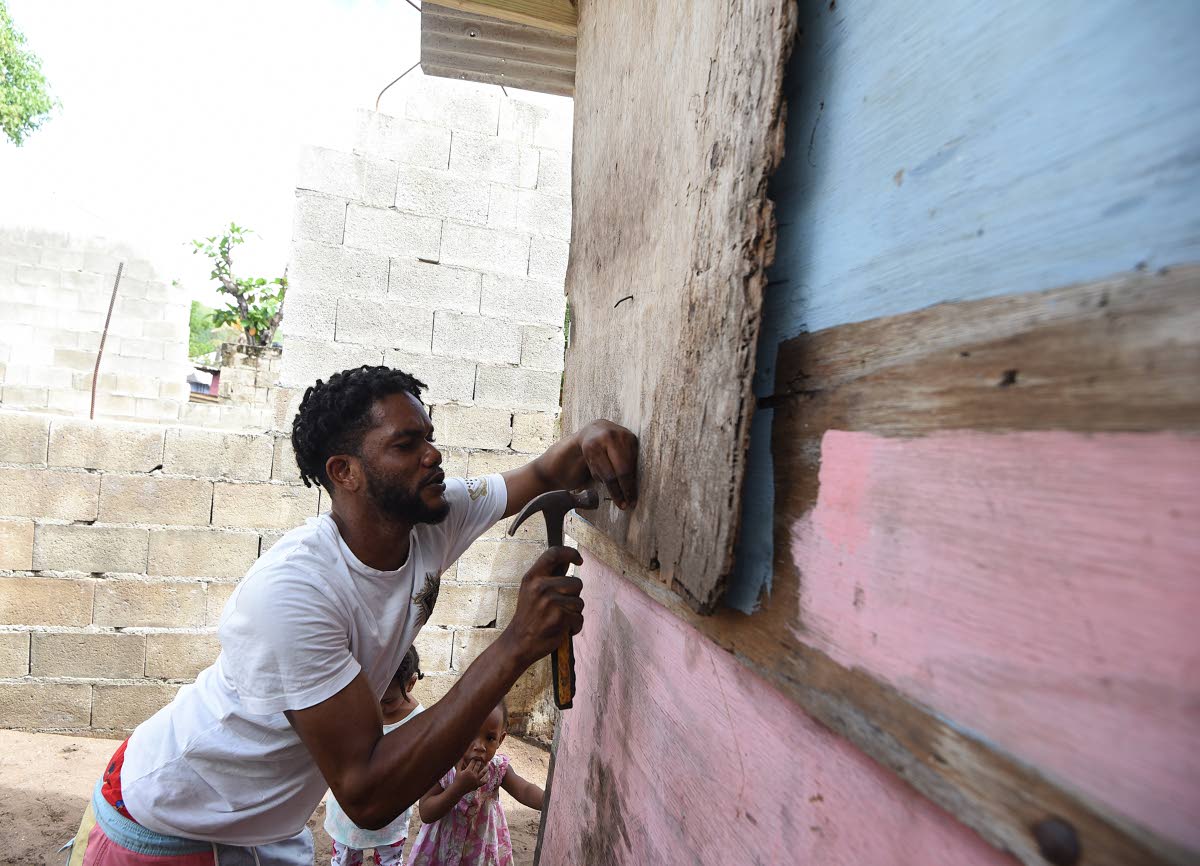 Devon Osbourne battens down a section of his house in Compound, Alligator Pond, Manchester, as he prepared for the arrival of Hurricane Melissa.