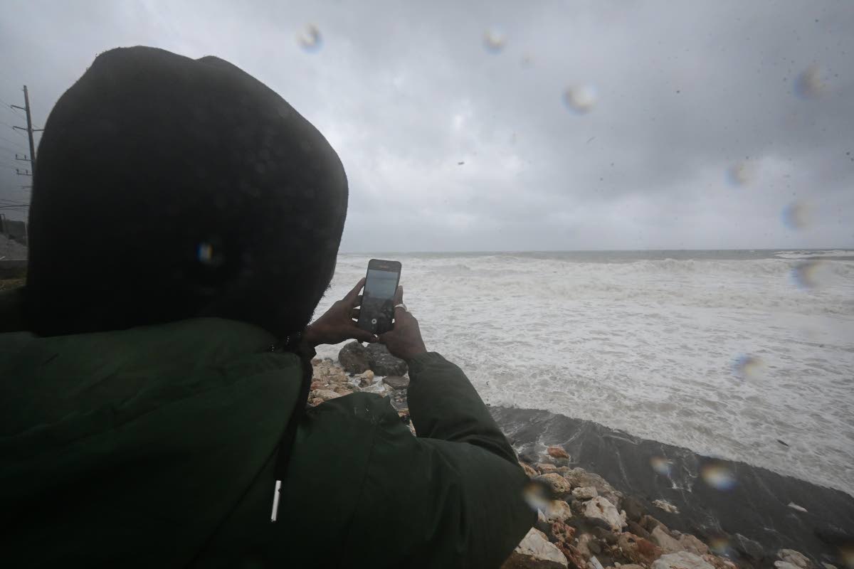 Howard Henry records the weather conditions on his cellphone by the shoreline in Seven Miles, Bull Bay 