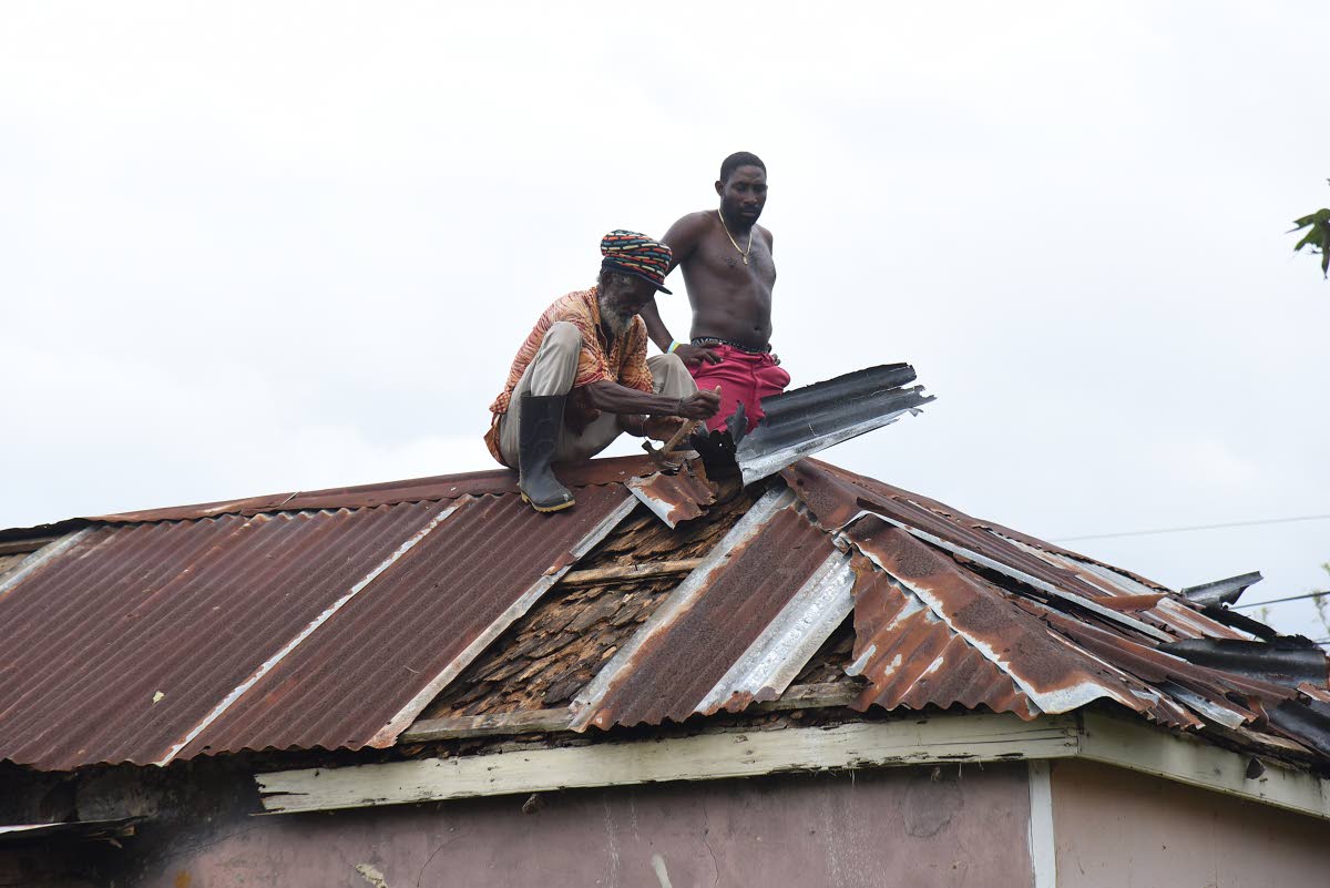Two men effect repairs to the roof of a house in Clarks Town, Trelawny, after the passage of Hurricane Melissa.