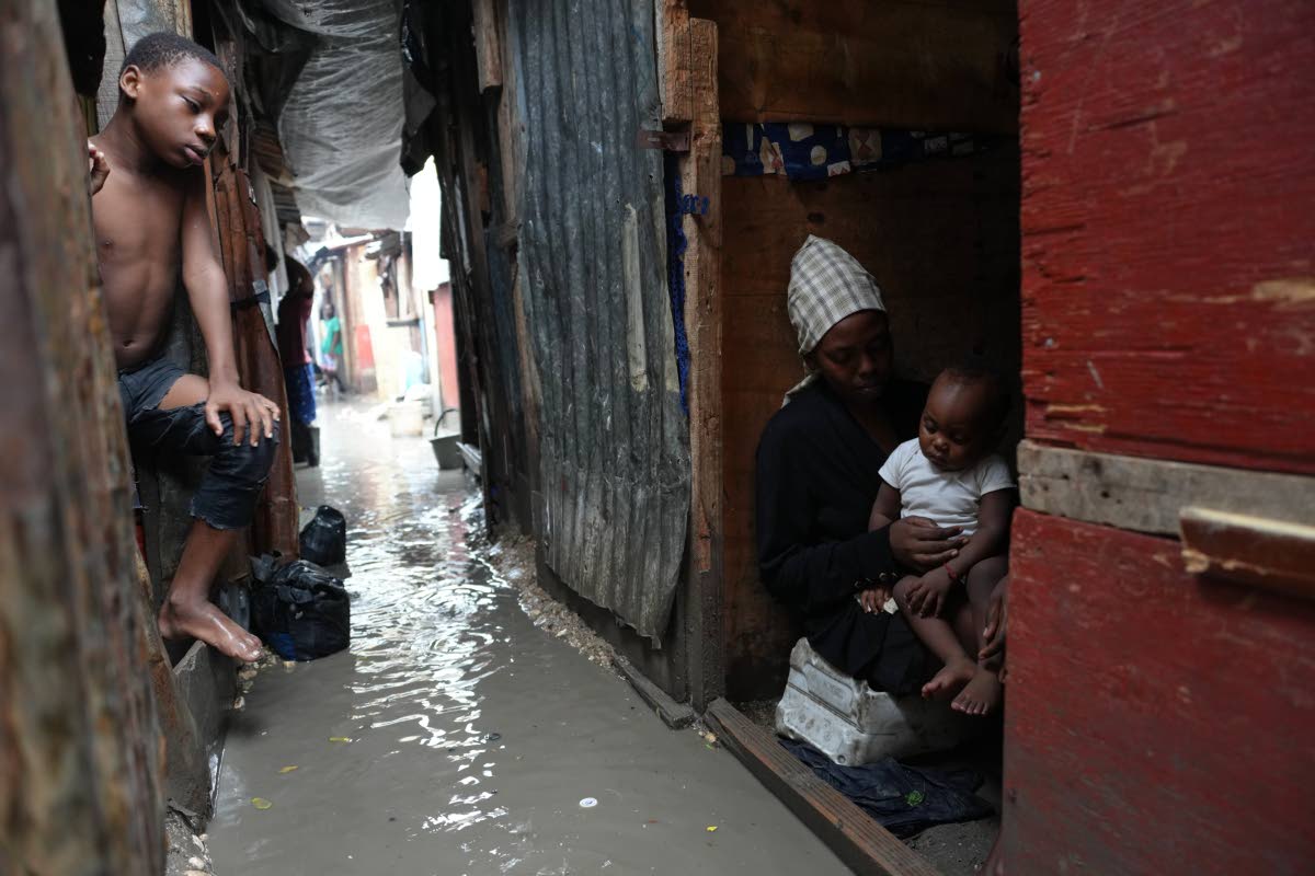 People stay inside a shelter for families displaced by gang violence, flooded by rain brought by Hurricane Melissa, in Port-au-Prince, Haiti, Wednesday, October29, 2025. (AP Photo/Odelyn Joseph)