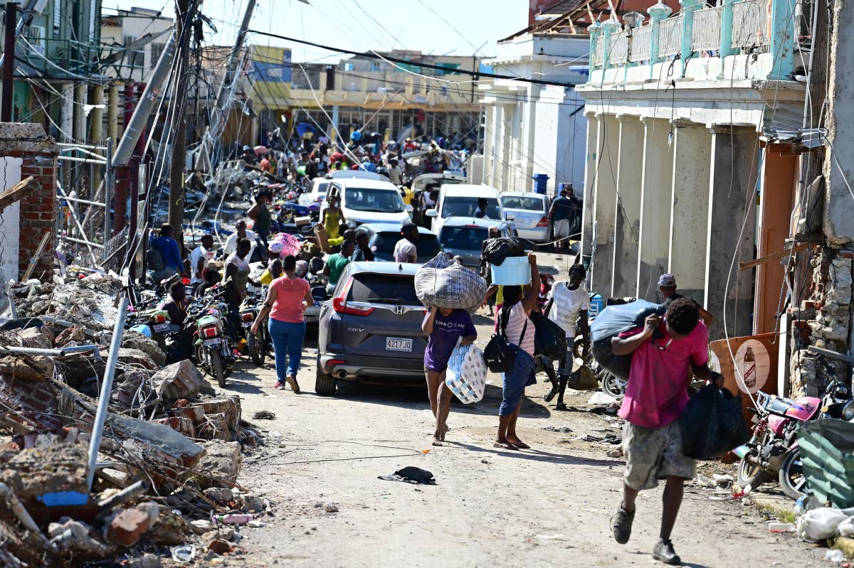 Persons travelling with supplies along Crane Road in Black River St Elizabeth, after Hurricane Melissa.
