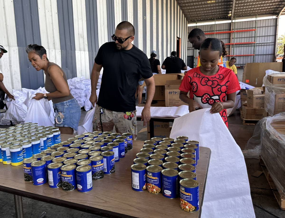 International recording artiste Sean Paul (centre), his sister-in-law Winsome Henriques (left), and a volunteer of the Sean Paul Foundation, Alana Thomas, get ready to  package food items during their visit to the Food For The Poor Jamaica. 