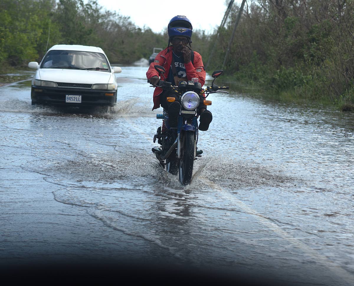 A motor cyclist rides through flood waters along Fore Shore Road in Falmouth, Trelawny last week,