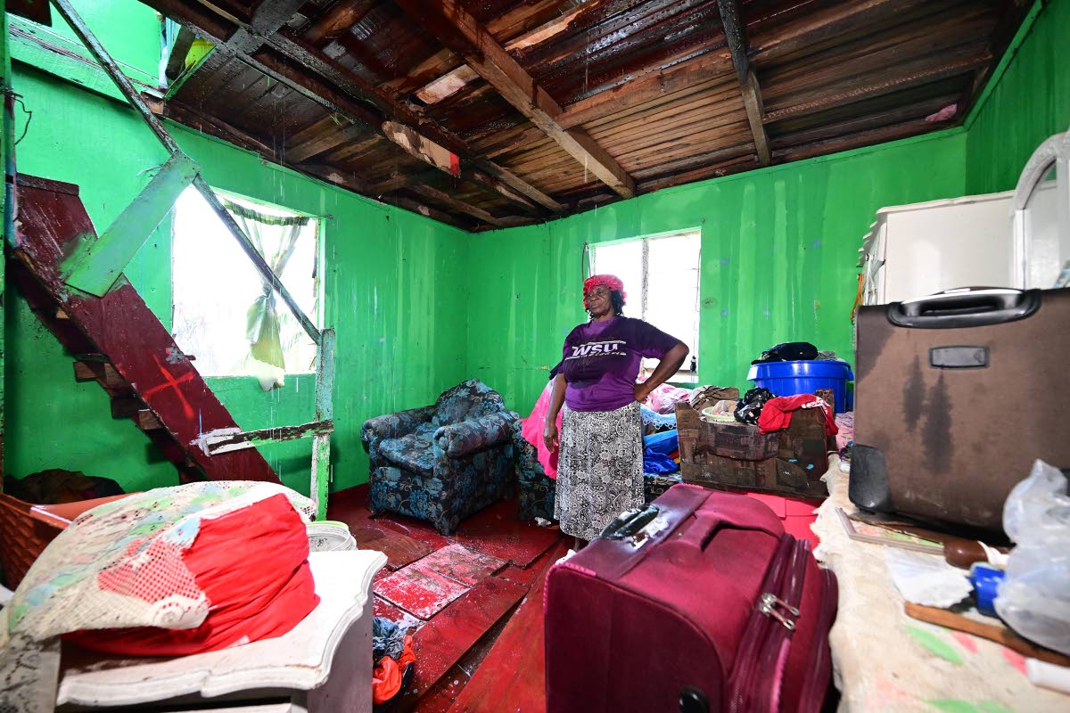 Veronica Grant stands in a room of her Montpelier home in Hanover. Water falls through the floor above as her home lost its roof during the hurricane. 