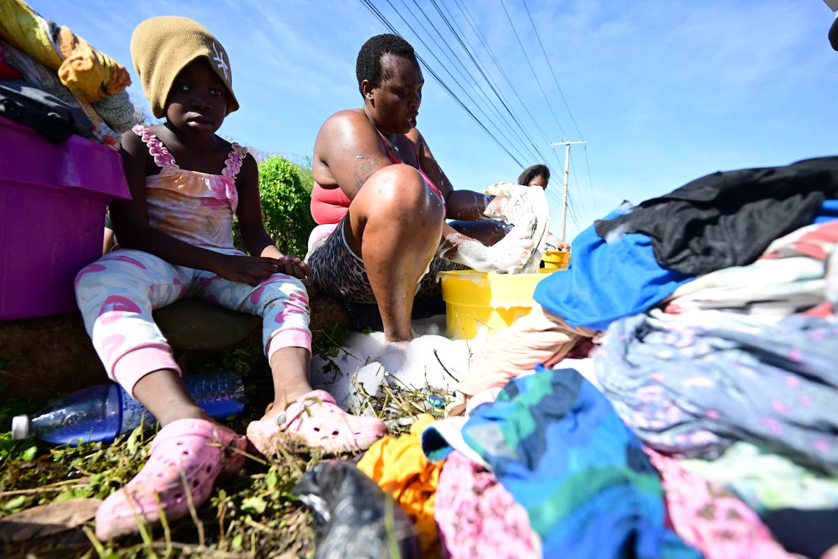 Stacy (right), a resident of Montpelier in St James, is seen at the Blue Hole river along the Sandy Bay main road in Hanover, washing clothes for her children and herself as there has been no water supply at home since the passing of Hurricane Melissa.