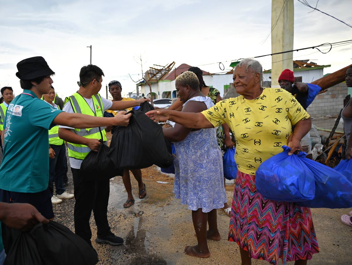 Members of the Chinese community in western Jamaica distribute care packages to residents of Parottee in St Elizabeth on Wednesday. 