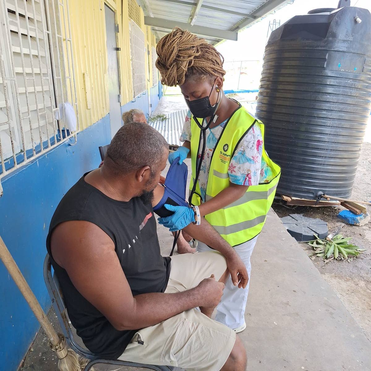 A volunteer from St John Ambulance and JN Group checks a resident’s blood pressure during a first-aid outreach in hurricane-hit St Elizabeth and Westmoreland.