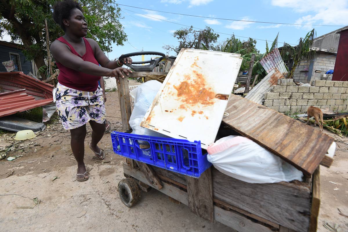 A young woman uses a cart to remove debris from her home in Mongro, Falmouth in Trelawny, the day after Hurricane Melissa devastated the area.