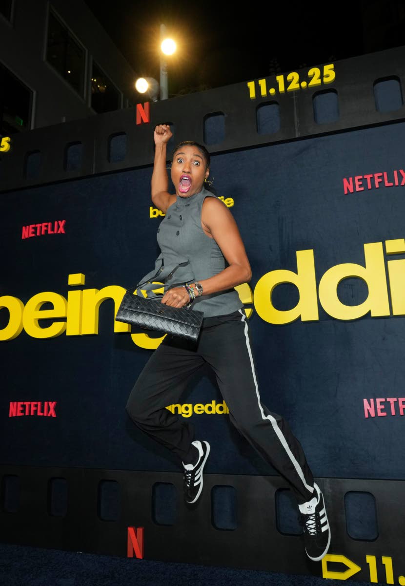Basketball player Angel McCoughtry is caught in a dunk pose on the blue carpet. 
