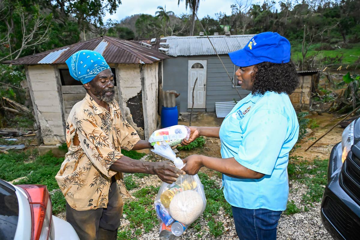 Parish Manager for Manchester in the Ministry of Labour and Social Security, Audrey Royal, hands a care package to small farmer Leroy Blake during a visit to Williamsfield, Manchester, on November 6, to do damage assessment and provide relief assistance to