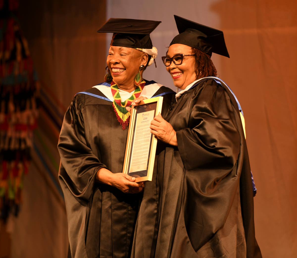 Dr Amina Blackwood-Meeks (left), a cultural architect and educator, happily accepts her Lifetime Achievement award from Dorrett Campbell, interim principal of the Edna Manley College of the Visual and Performing Arts, during the institution’s graduation 