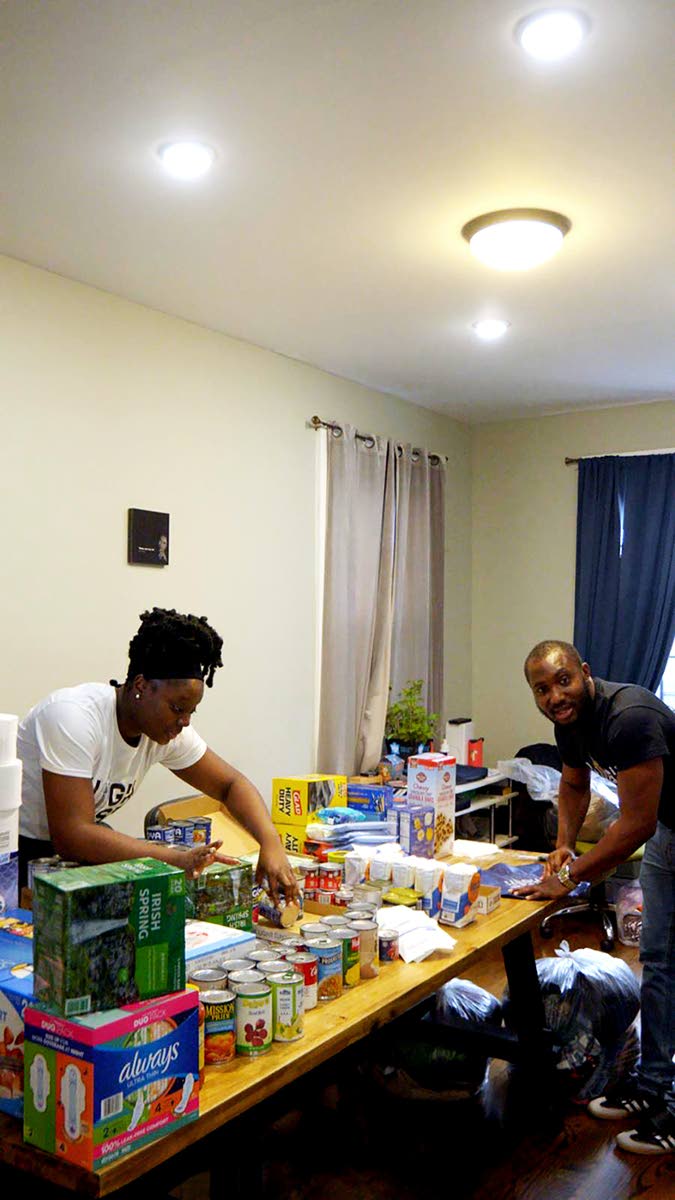 Shenica Springer, co‑founder of the High‑Rise Tribe, sorts relief items with a volunteer for shipment to Jamaica. 