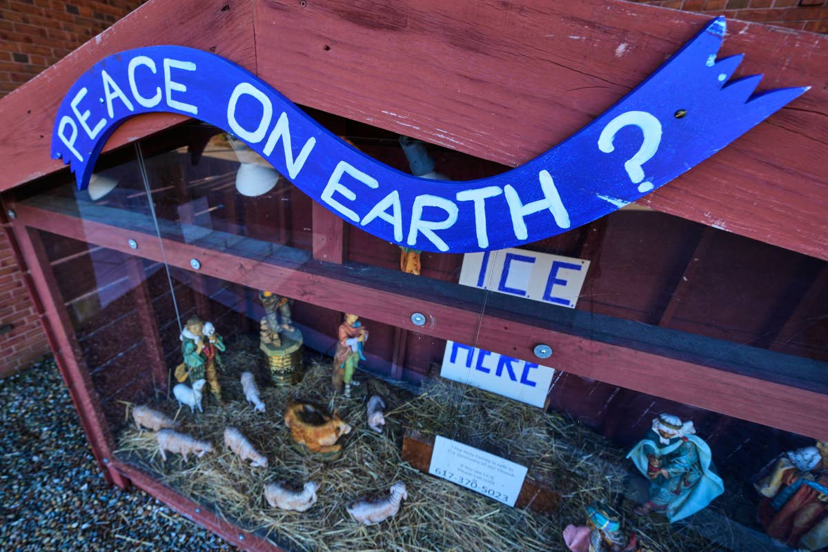 A ‘PEACE ON EARTH?’ sign is posted on the top of a nativity display, which features an ICE WAS HERE sign in the spot for the baby Jesus, outside St Susanna Church in Dedham, Mass on December 9.