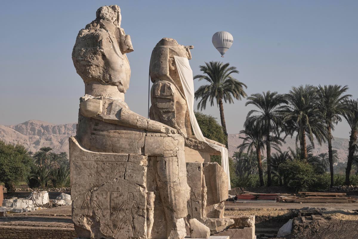 A hot-air balloon flies over the assembly of two giant alabaster statues for Pharaoh Amenhotep III, before the official opening, in the southern city of Luxor, Egypt.