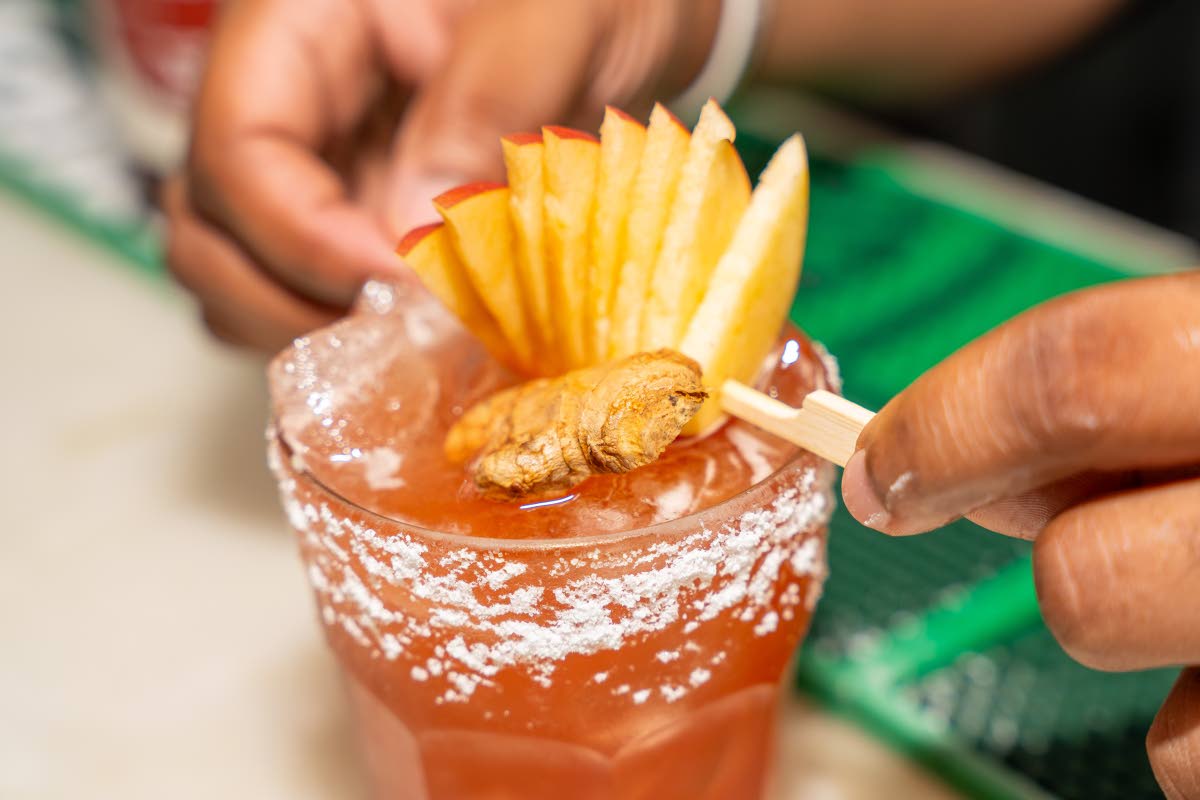 Mixologist Theo Miller garnishes the D&G velvet sorrel cocktail with a fan of thinly sliced apple and a piece of ginger.