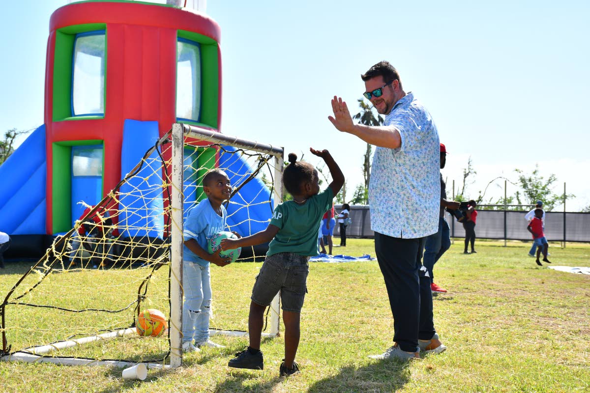 United States Travel Adviser Clint Finch celebrates with his young teammate during a game of football at the Sandals Foundation Christmas Treat.