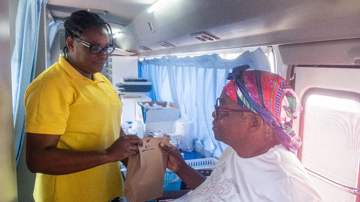 Robertha Carter (left), pharmacy technician, National Health Fund, presents to Dorrett Burton her free prescription drugs after seeing the doctor at the Hurricane Recovery Health Clinic in Thornton, St Elizabeth.