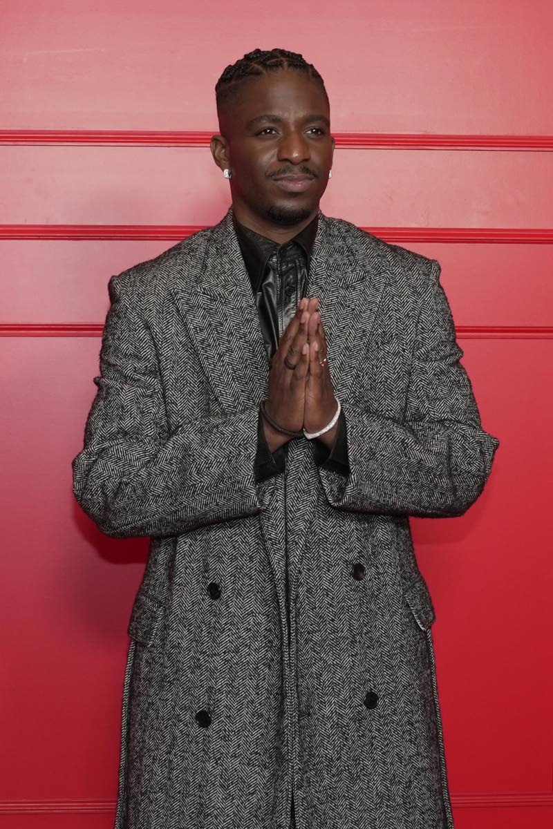 Samuel Arnold in a grey Lanvin flannel double-breasted coat, matching trousers, and a leather undershirt. 