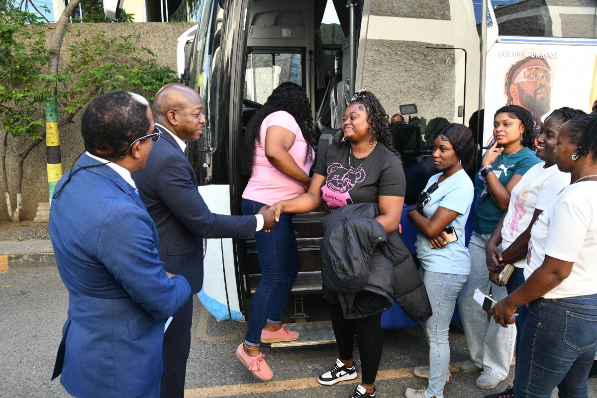 Labour and Social Security Minister Pearnel Charles Jr (second left) shakes hands with farm worker Zeneice Nixon at a send-off ceremony for 95 workers who departed the island for Toronto, Canada, last April under the Canadian Seasonal Agricultural Workers 