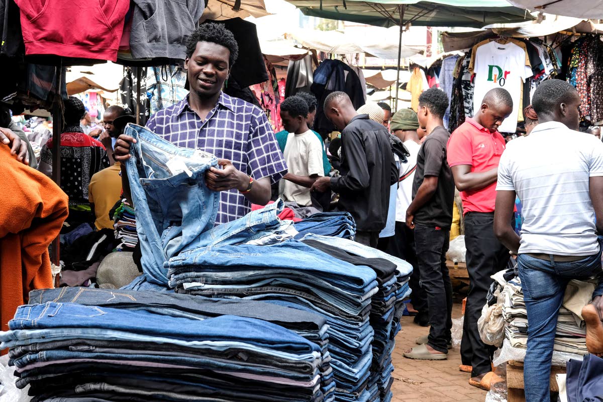 A second-hand clothes retailer folds second-hand jeans at his stall at Owino Market in Kampala, Uganda.