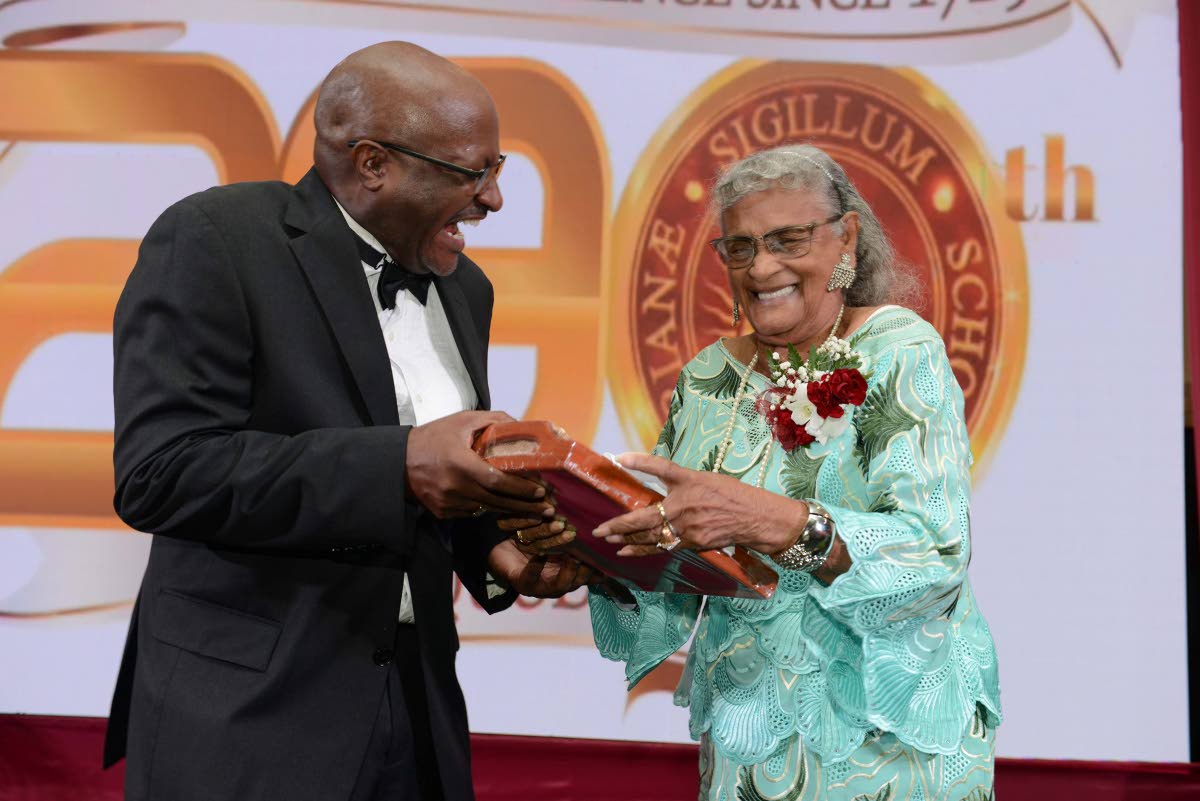 Wolmerian and radio personality Francois St Juste presents a plaque to fellow Wolmerian and media veteran Alma Mock Yen in 2019. 