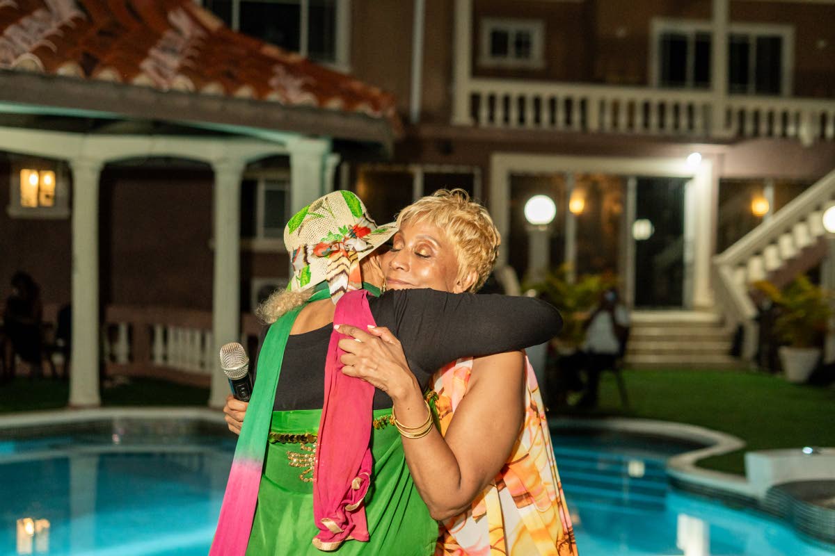 Dr Marcia Griffiths (left) shares a warm embrace with fellow reggae songstress Nadine Sutherland during the postgraduation reception at her home, moments after Sutherland delivered a moving tribute in honour of the newly conferred cultural icon.