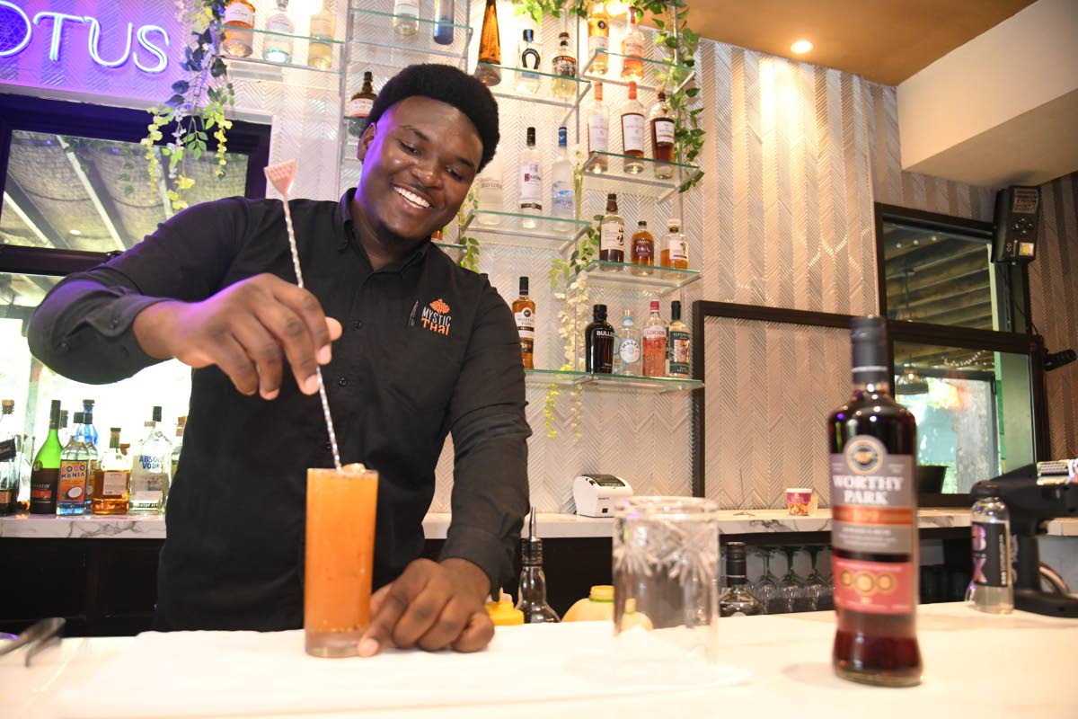 Mixologist Conroy Plummer happily prepares a tall glass of the pasi-flora.