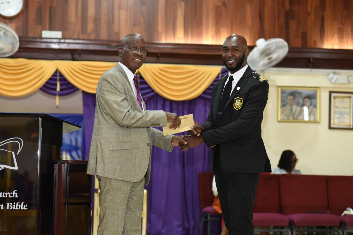 Customs Officer Earl Rayson (right) presents an undisclosed financial donation to Reverend Michael Hammond for the ministries of the First Church of the Open Bible. 