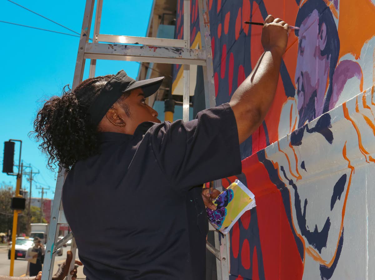 Visual artist, Kristina Rowe, in her creative element painting a mural of the late reggae singer, Alton Ellis.