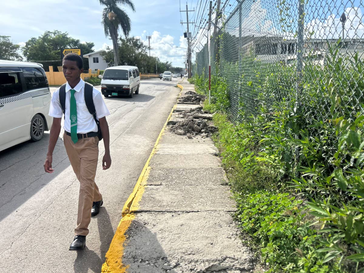 
Students and other pedestrians are forced to walk along the roadway in Savanna-la-Mar as the sidewalk along Barracks Road collapses into the drainage system.