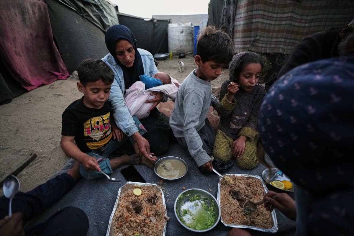 Displaced members of the Al-Zamli family break their fast on the first day of Ramadan inside their tent in Khan Younis, Gaza Strip, Wednesday, February 18.