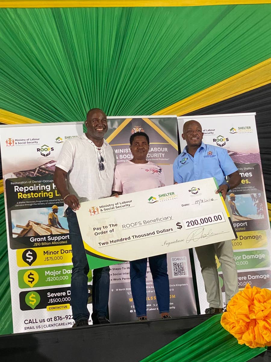 Myrtle Alcock (centre) of Darliston, Westmoreland, receives a symbolic cheque valued at $200,000 under the Government’s Restoration of Owners or Occupants of Family Shelter (ROOFS) Programme, administered through the Ministry of Labour and Social Securit