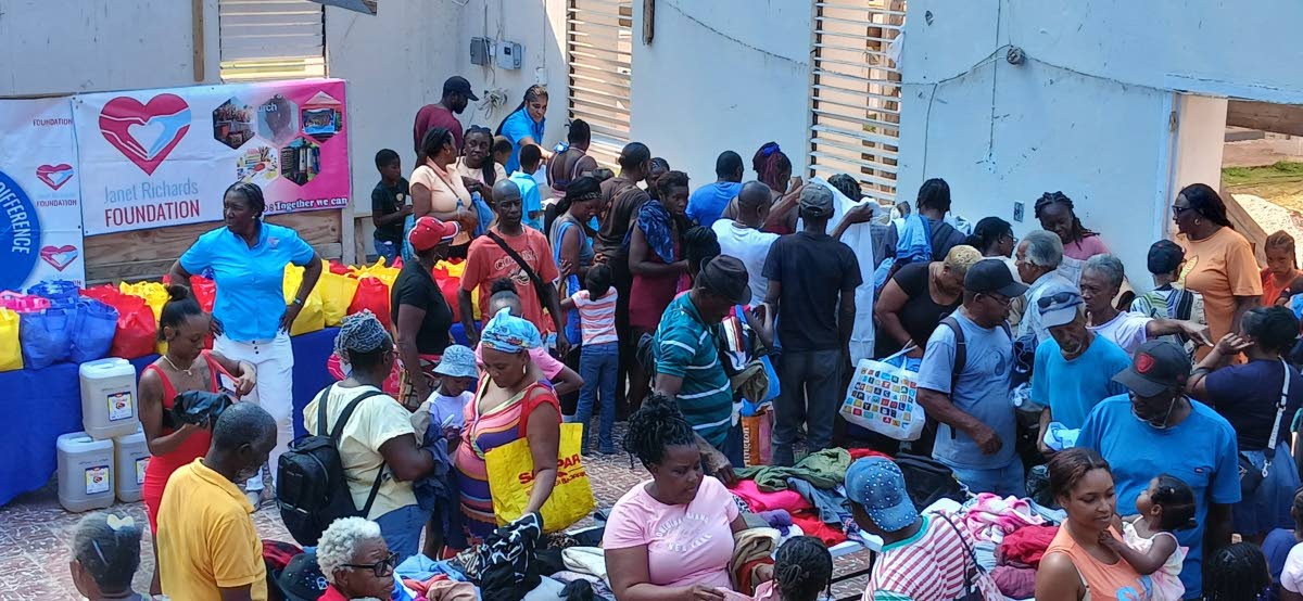 Janet Richards (left), the founder of the Janet Richards Foundation, looks on as residents of Chatham, St James, congregate at the grounds of the Bethtephil Baptist Church in the community for the distribution of care packages by the foundation last Saturd