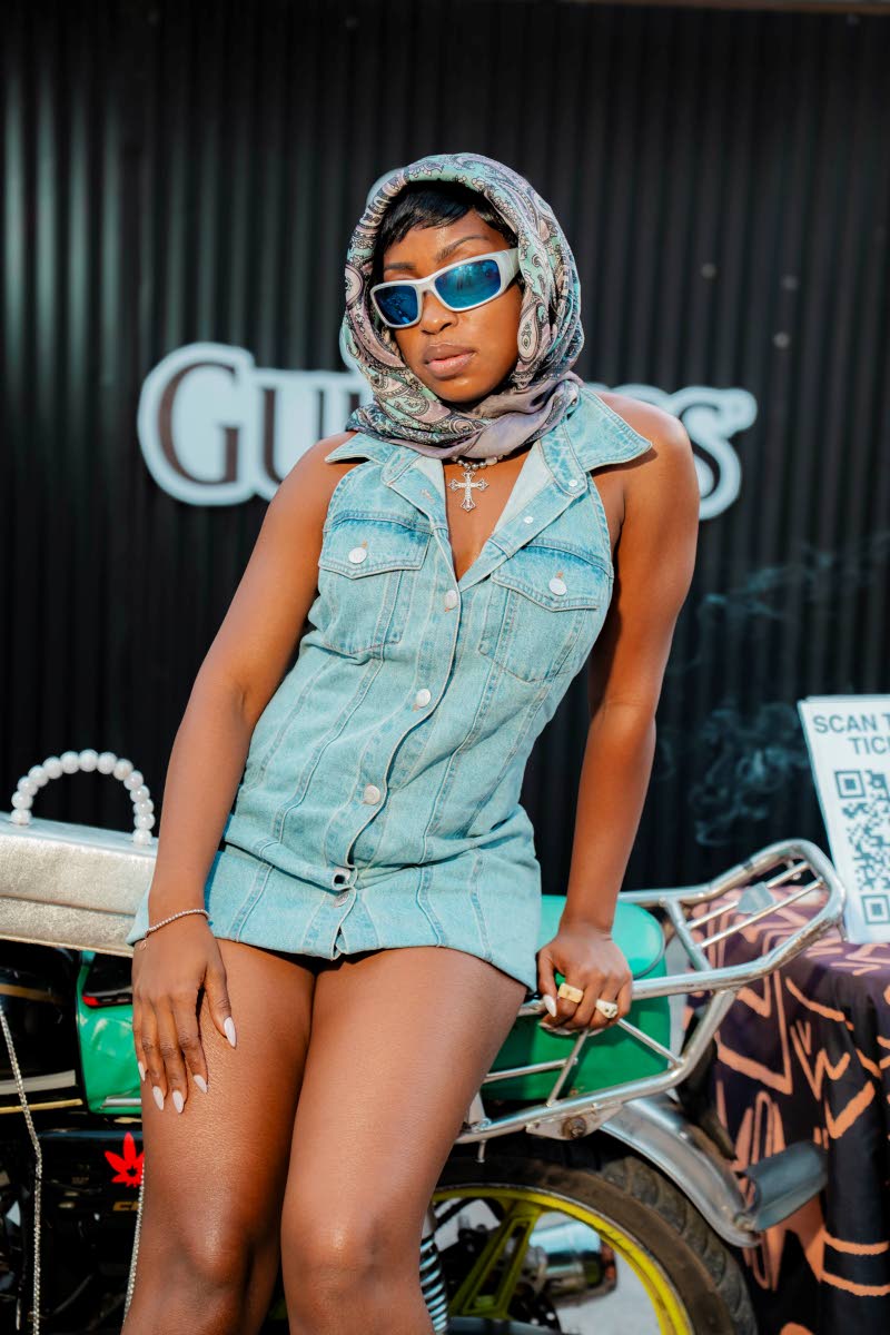 Shanelle Katina, road manager, Lila Iké, steps out in a light-wash denim mini with blue-tinted shades and a paisley headscarf.