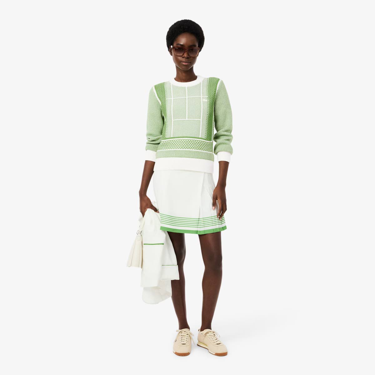 What’s trending in casual wear? Tomiwa gives wardrobe ideas in this Lacoste tennis court graphic jacquard sweater paired with a fluid crepe pleated skirt and the brand’s Aura leather sneakers.
