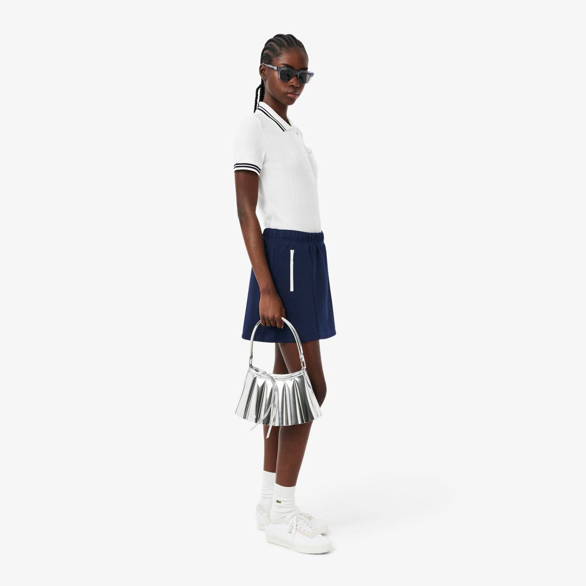 SAINT’s African beauty wears the Lacoste short pocket detail skirt, a slim fit trim detail polo shirt, with the small Lenglen leather bag in hand.