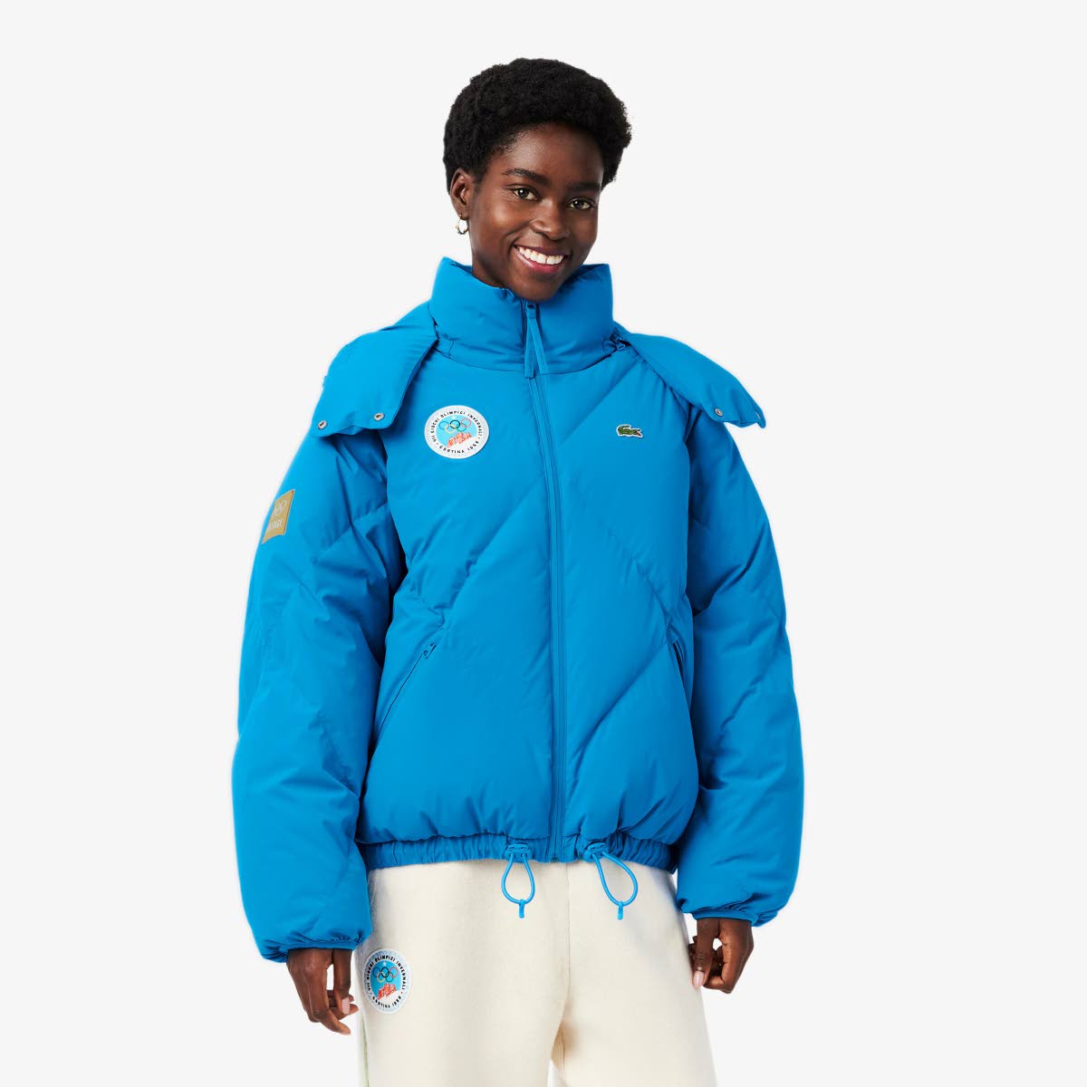 Blending retro-winter sport spirit and Alpine elegance, Tomiwa rocks the Lacoste x Olympic Heritage Cortina d’Ampezzo 1956 puffed jacket and wool pants. 