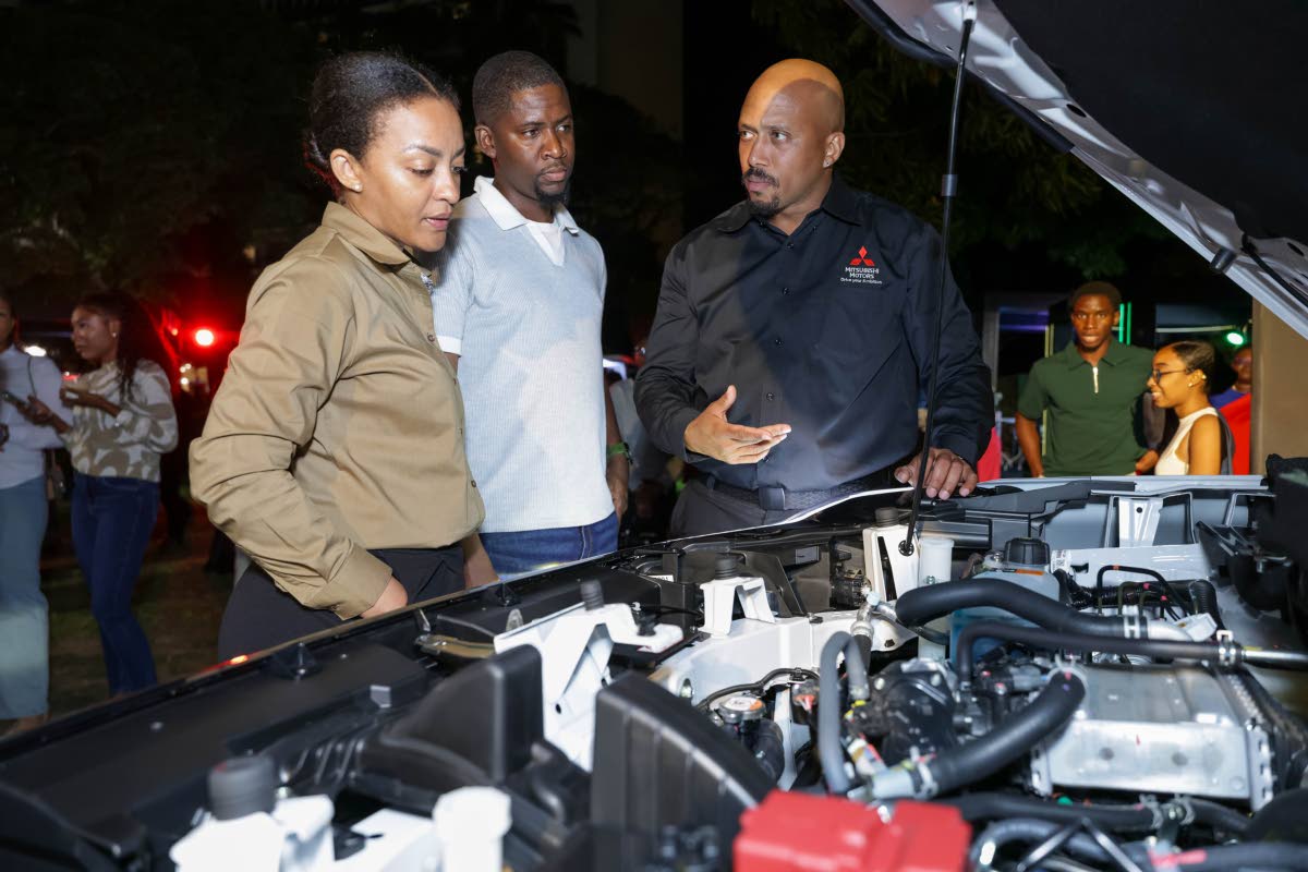 (L-R) Guests, Kerry Lediard and Jero Brown, get an up-close look at the Destinator’s advanced 1.5L turbocharged engine as Jerome Boulin, Sales Executive at Mitsubishi Motors Jamaica, demonstrates its capabilities.