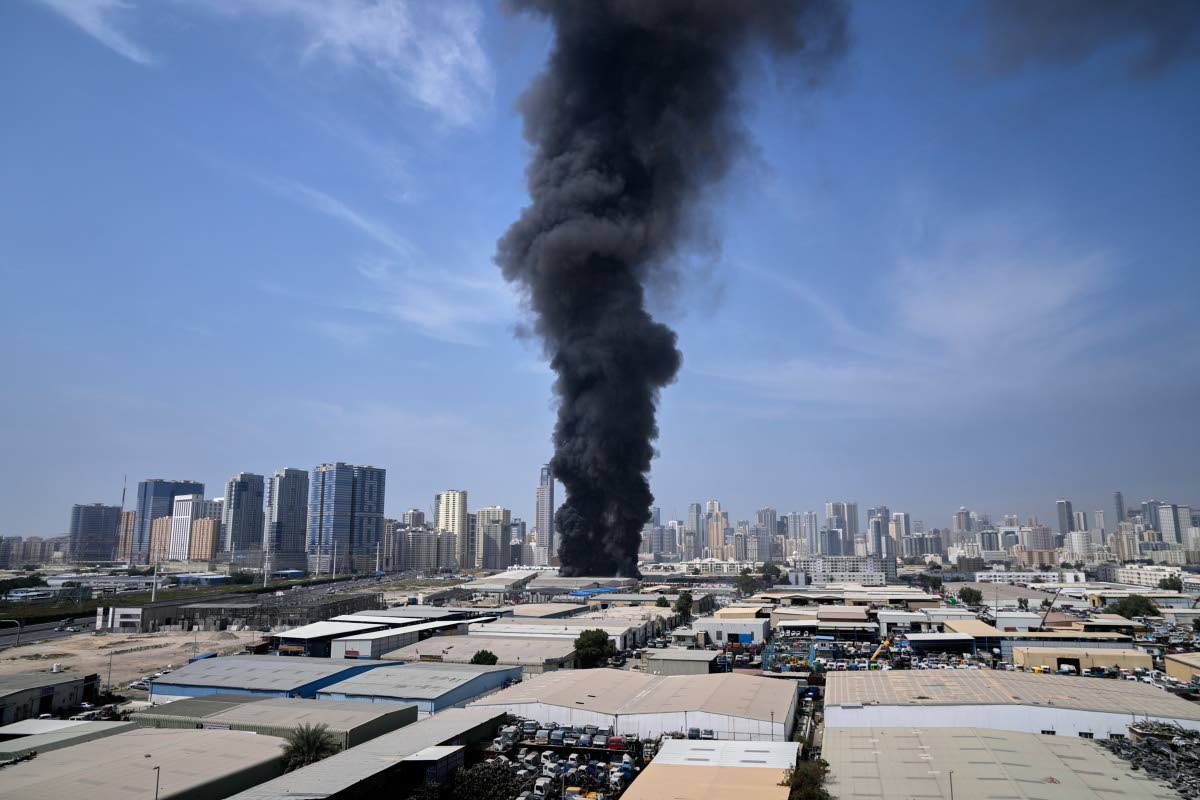A black plume of smoke rises from a warehouse at the industrial area of Sharjah City in the United Arab Emirates following reports of Iranian strikes in Dubai, United Arab Emirates, Sunday, March 1, 2026. 