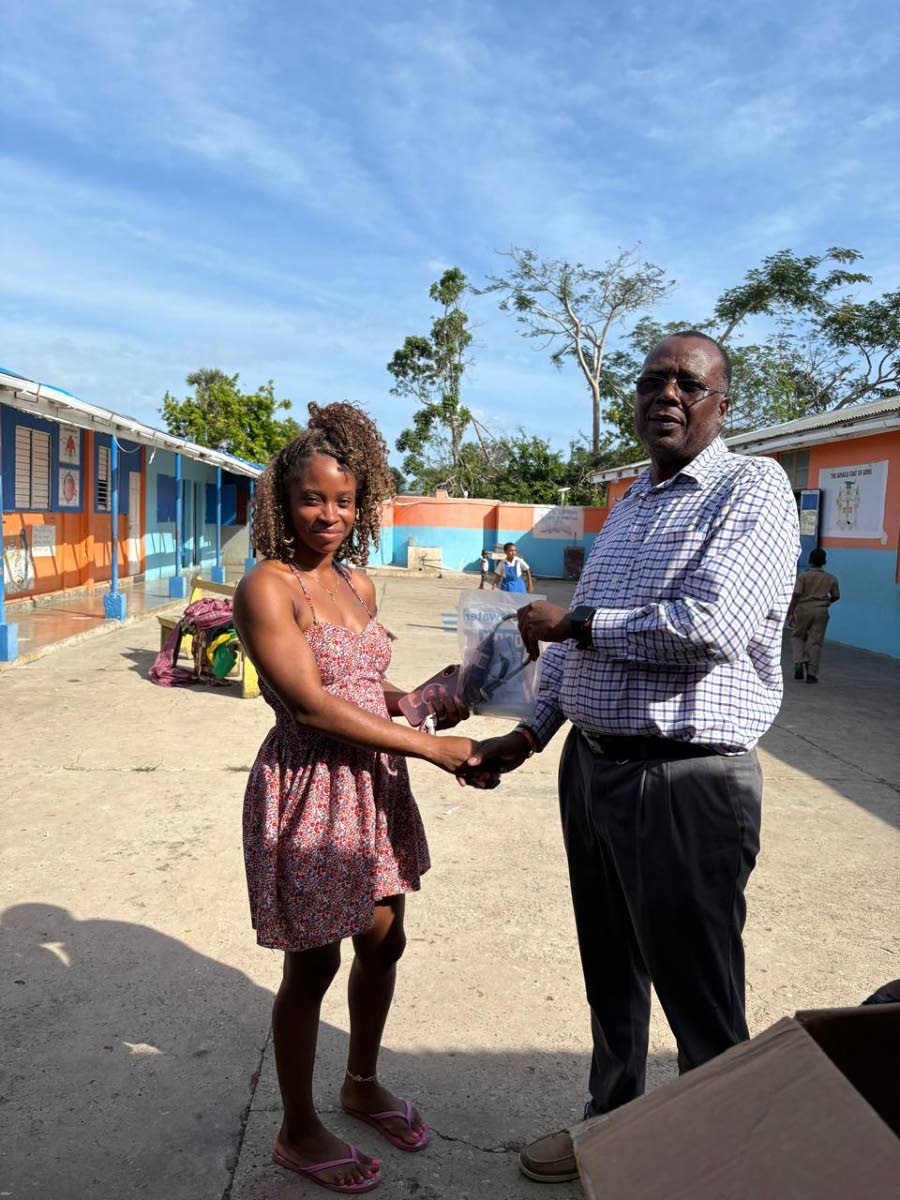 Gerald Miller (right), health promotion and education officer for Westmoreland, hands over a Drop Filter to a parent at Broughton Primary School after demonstrating how to use the device to access safe drinking water.