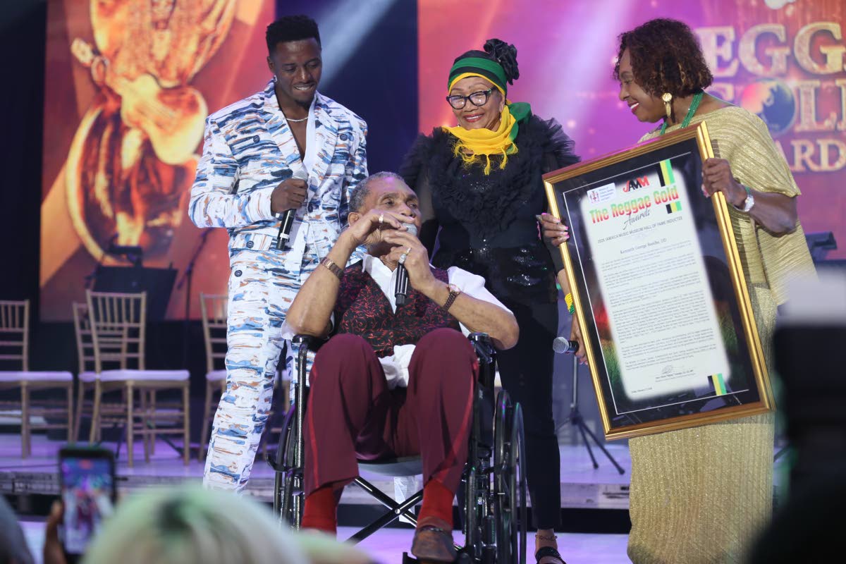 Kenneth Boothe (centre) is flanked by (from left) reggae artiste Romain Virgo, Queen of Reggae Marcia Griffiths, and Olivia Grange at the Reggae Gold Awards last Friday, as he receives his official plaque for induction into the Jamaica Music Museum