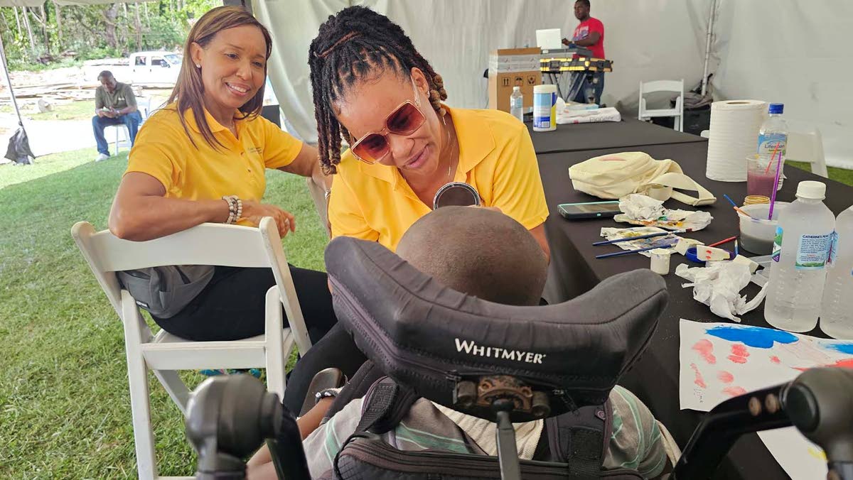 Judith Pryce (left) general manager of the Tony Thwaites Wing, (UHWI) looks on as a TTW volunteer staff member paints the face of one of the youngsters at Blessed Assurance Children’s Home on Saturday February 28.