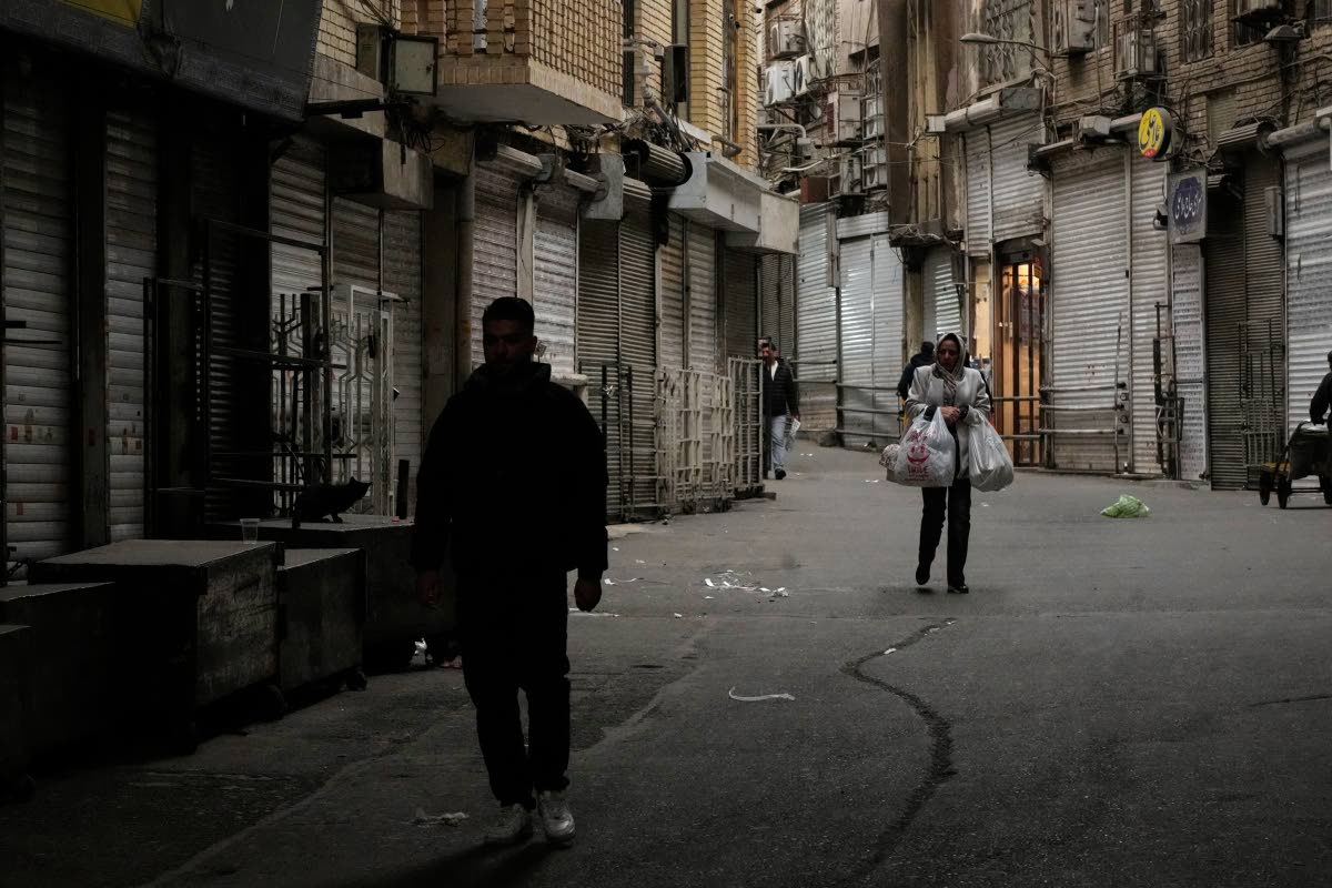 A woman carries her groceries as people walk along the mostly empty Tehran traditional main bazaar, where most shops are closed, in Tehran, Iran on March 10, 2026. (AP Photo/Vahid Salemi)